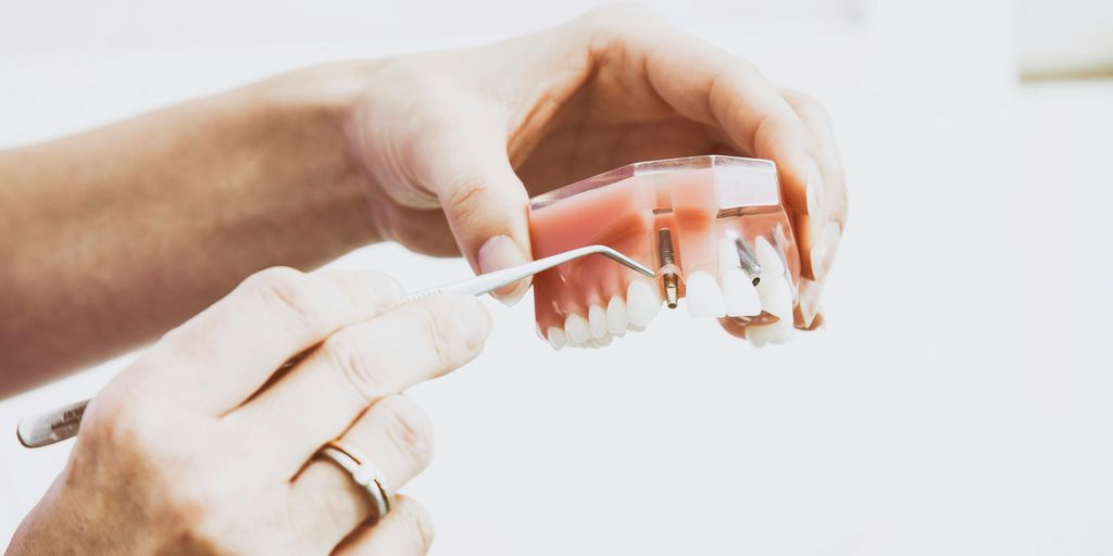person wearing silver-colored ring while holding denture